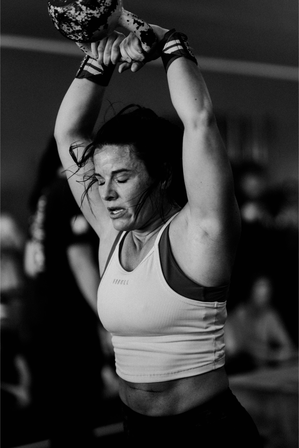Black and white photo of a woman lifting weights with a blurred background
